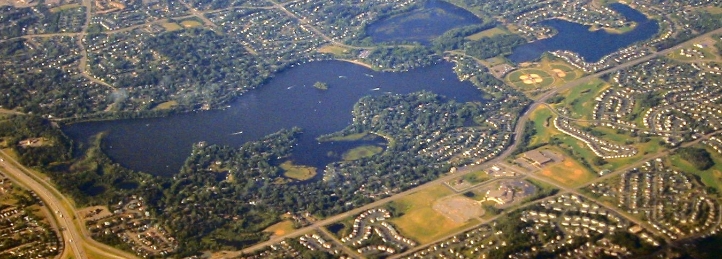 Aerial view of suburban neighborhoods surrounding lakes, parks, and winding residential streets.