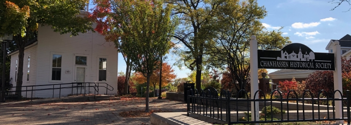 Entrance to the Chanhassen Historical Society with autumn trees, walkway, and historic white building.