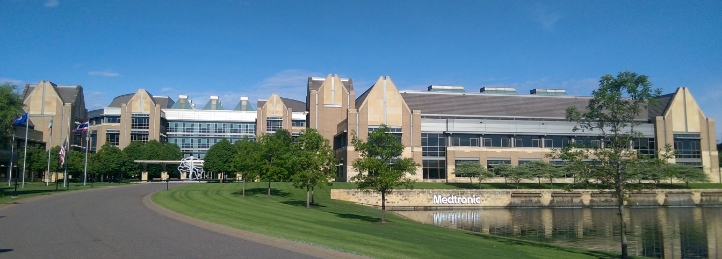 Modern Medtronic corporate campus with landscaped grounds, reflective pond, and contemporary office buildings.
