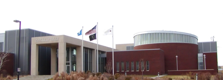Modern government or civic building with curved architecture, flagpoles, and landscaped entrance.