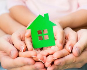 family-holding-green-paper-house-in-hands