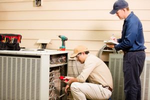 two-air-conditioning-techs-working-on-outdoor-unit