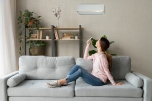 woman-sitting-on-couch-with-controller-for-ductless-air-handler