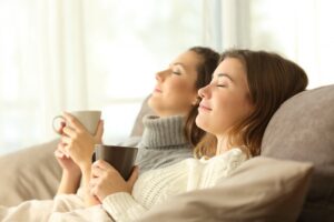 two-women-in-sweaters-leaning-back-on-couch