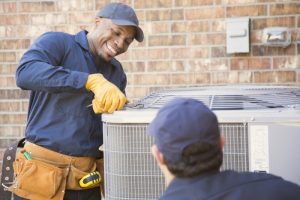 smiling-HVAC-technician-working-on-an-outdoor-unit